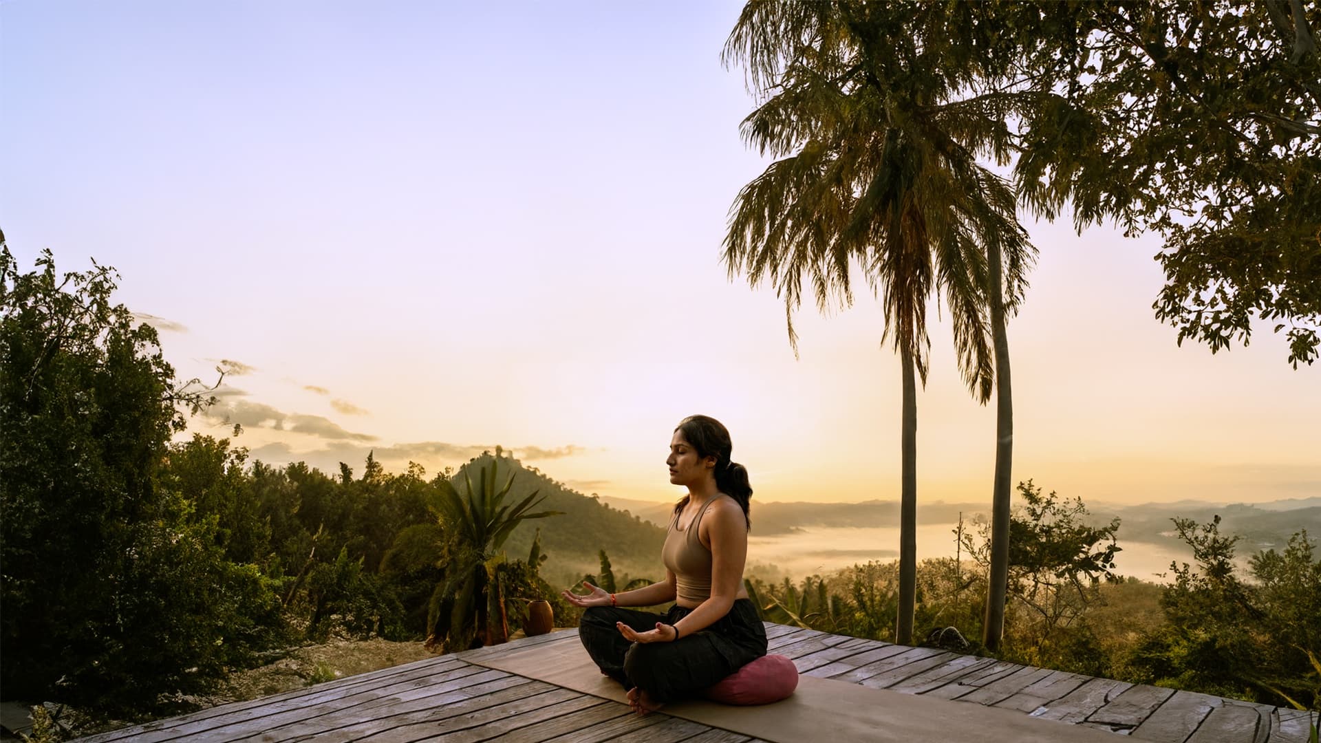 Sunrise meditation on a wooden deck above a misty valley